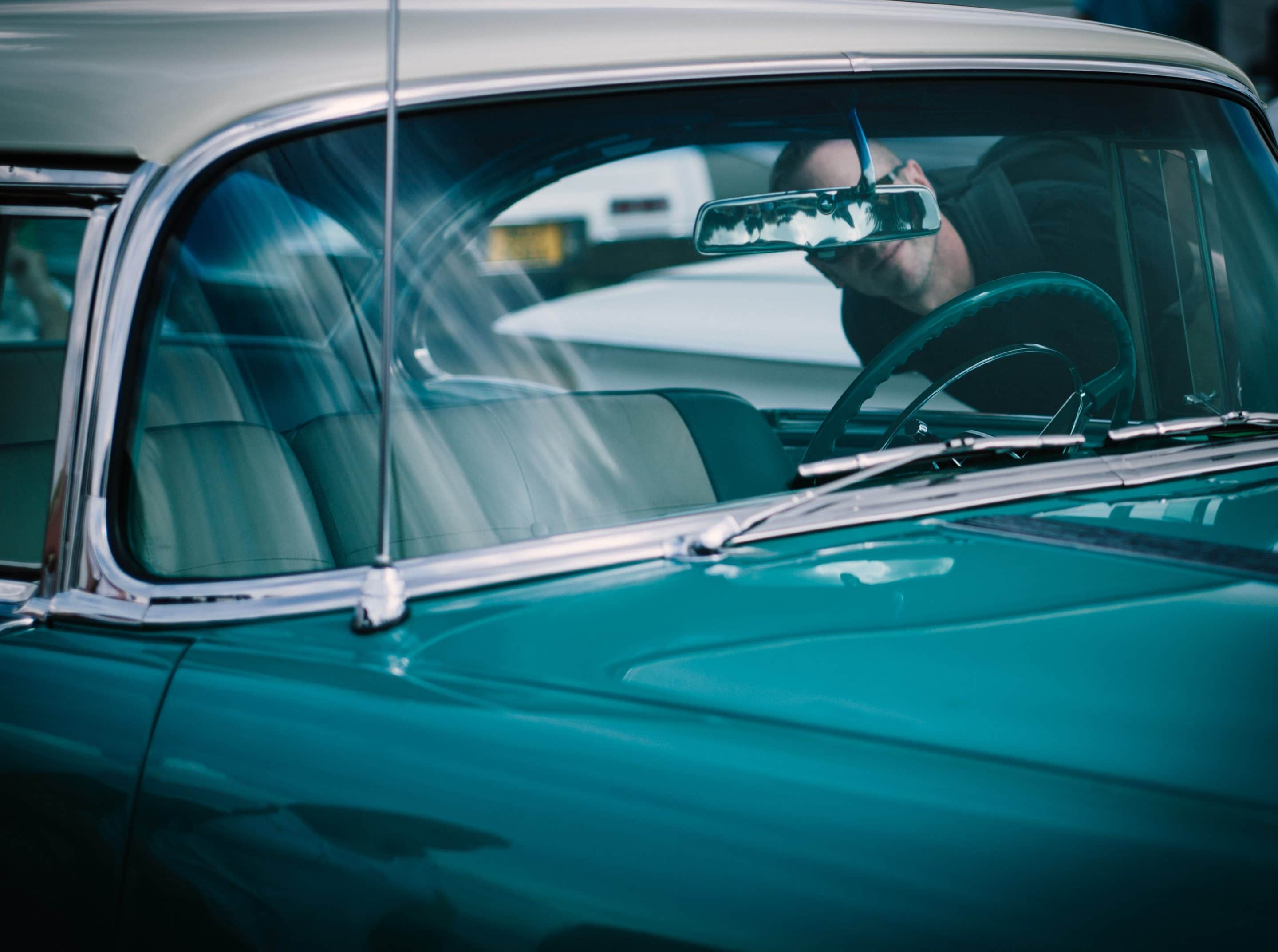 Man peering into blue car for sale